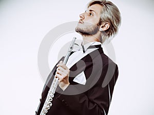 Male flutist wearing tailcoat holds flute