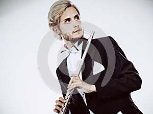 Male flutist wearing tailcoat holds flute