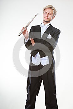 Male flutist wearing tailcoat holds flute