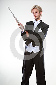 Male flutist wearing tailcoat holds flute