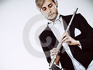 Male flutist wearing tailcoat holds flute