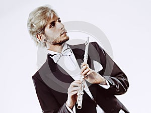 Male flutist wearing tailcoat holds flute