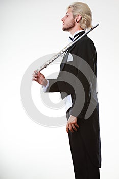 Male flutist wearing tailcoat holds flute