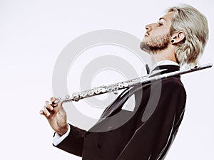 Male flutist wearing tailcoat holds flute