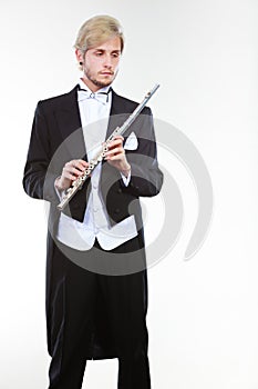 Male flutist wearing tailcoat holds flute