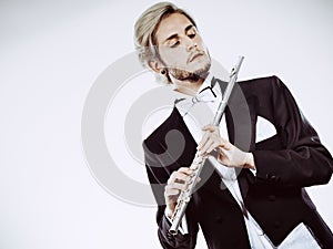Male flutist wearing tailcoat holds flute