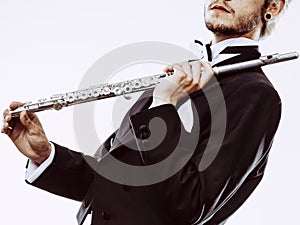 Male flutist wearing tailcoat holds flute