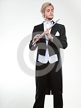 Male flutist wearing tailcoat holds flute