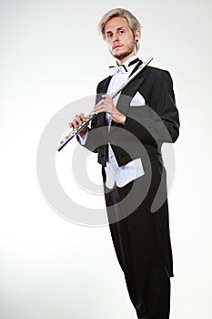 Male flutist wearing tailcoat holds flute