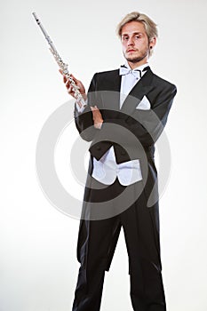 Male flutist wearing tailcoat holds flute