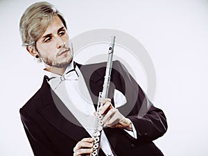 Male flutist wearing tailcoat holds flute