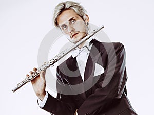 Male flutist wearing tailcoat holds flute