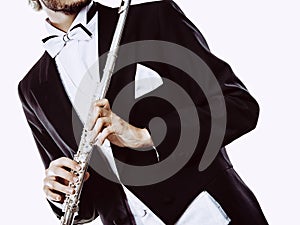 Male flutist wearing tailcoat holds flute