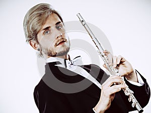 Male flutist wearing tailcoat holds flute