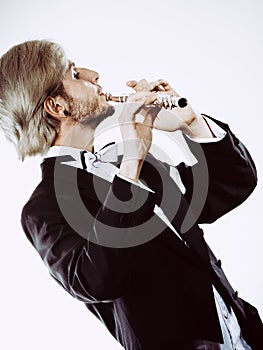 Male flutist wearing tailcoat plays flute