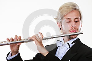 Male flutist wearing tailcoat plays flute