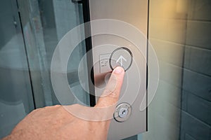 Male forefinger pressing on button up in front of the elevator