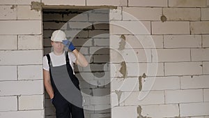 A male foreman stands in a doorway leaning against a wall at a construction site