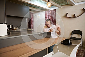 Male freelancer arguing during video conference, showing paper documents to his interlocutors during online meeting