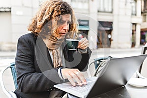 Male freelancer with coffee using laptop