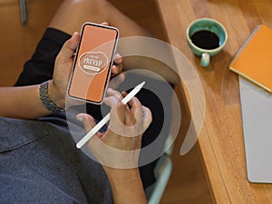 Male freelancer using mock up smartphone screen at worktable in home office room