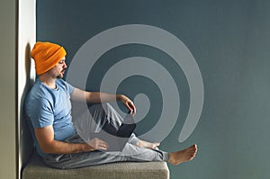 Male freelancer in yellow hat, blue t-shirt and gray pants works at computer