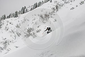 Male freerider in helmet, ski suit and goggles skiing on snow-covered slopes