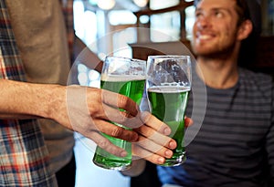 Male friends drinking green beer at bar or pub