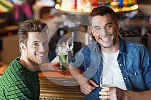 Male friends drinking green beer at bar or pub