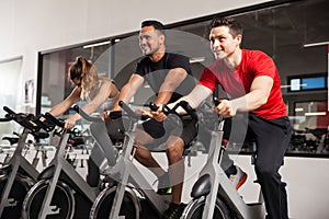 Male friends enjoying spinning in a gym