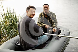 Male friends fishing on rubber boat in river