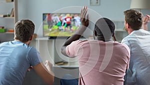 Male friends gather to watch football competition on big screen, sofa experts