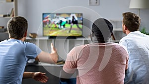 Male friends gather to watch football competition on big screen, sofa experts