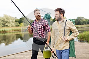 Male friends with net and fishing rods on lake