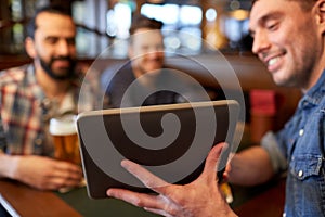 Male friends with tablet pc drinking beer at bar