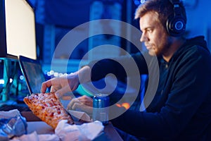 Male gamer eating pizza, night tournament