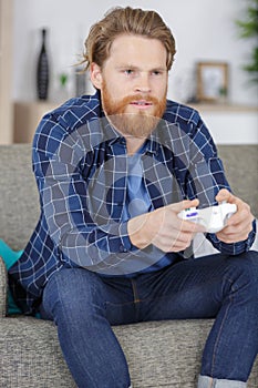 Male gamer using controlpad from sofa