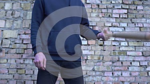 Male gangster with bat in hands on brick wall background, aggressive attack