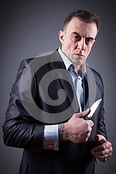 Male gangster in a business suit with a knife