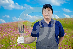 Male gardener hand holding garden tools and blurred background is flower garden