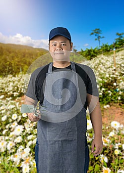 Male gardener hand holding garden tools and blurred background is flower garden