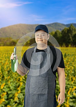 Male gardener hand holding garden tools and blurred background is flower garden