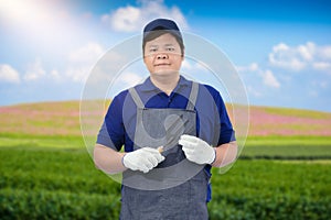 Male gardener hand holding garden tools and blurred background is flower garden