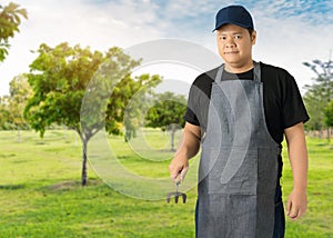 Male gardener hand holding garden tools and blurred background is fruit garden