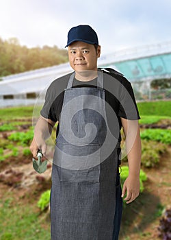 Male gardener hand holding garden tools and blurred background is vegetable garden