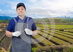 Male gardener hand holding garden tools and blurred background is vegetable garden