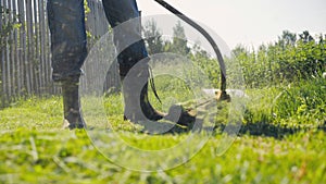 Male gardener mowing green lawn with manual gas grass mower, garden maintenance