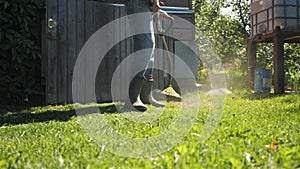 Male gardener mowing green lawn with manual gas grass mower, garden maintenance