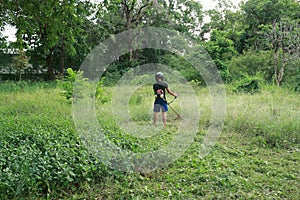 Male gardener using a lawn mower to mow the overgrown lawn. Garden care