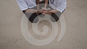 Male Gay Couple on the beach in the squatting position holding hands by the heart shape handwritten on the sand